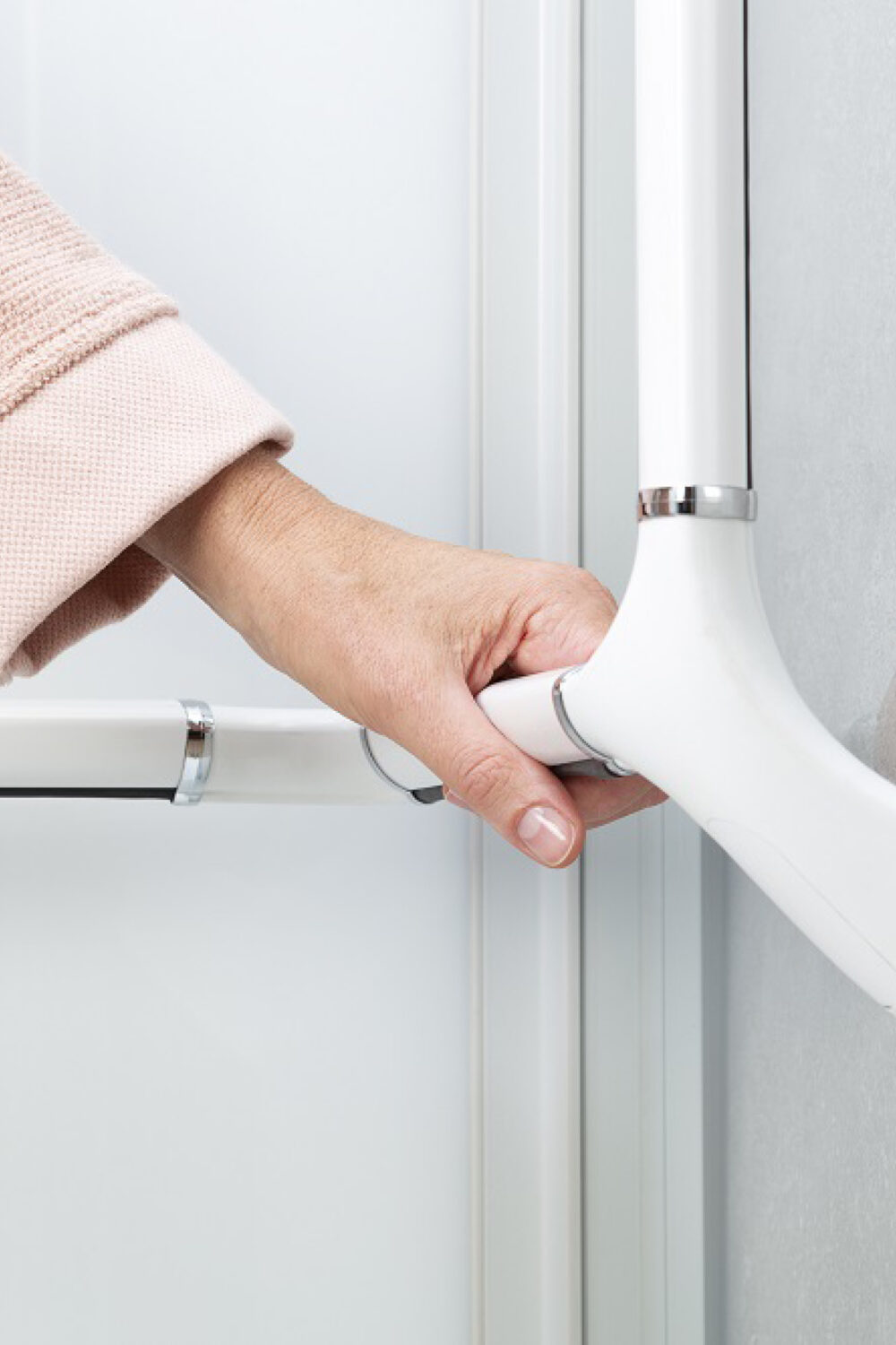 Eine Hand fasst an einen robusten Griff zum sicheren Einstieg in die Dusche.